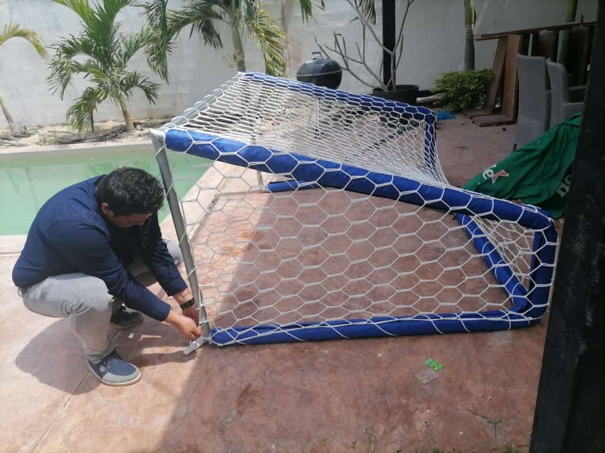 Reinier Coral ajustando la red hexagonal de una portería pequeña junto a una alberca