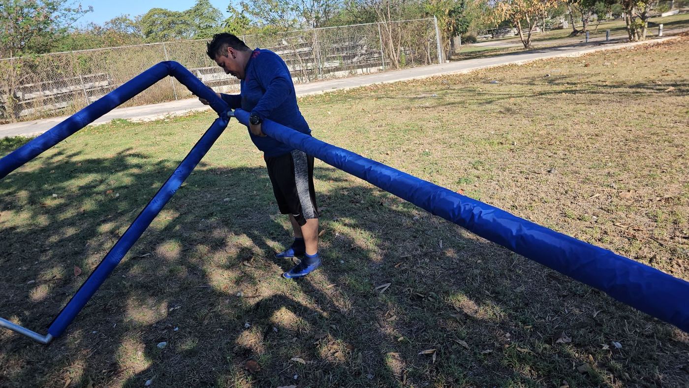 Técnico armando una portería de fútbol con tubos forrados en azul