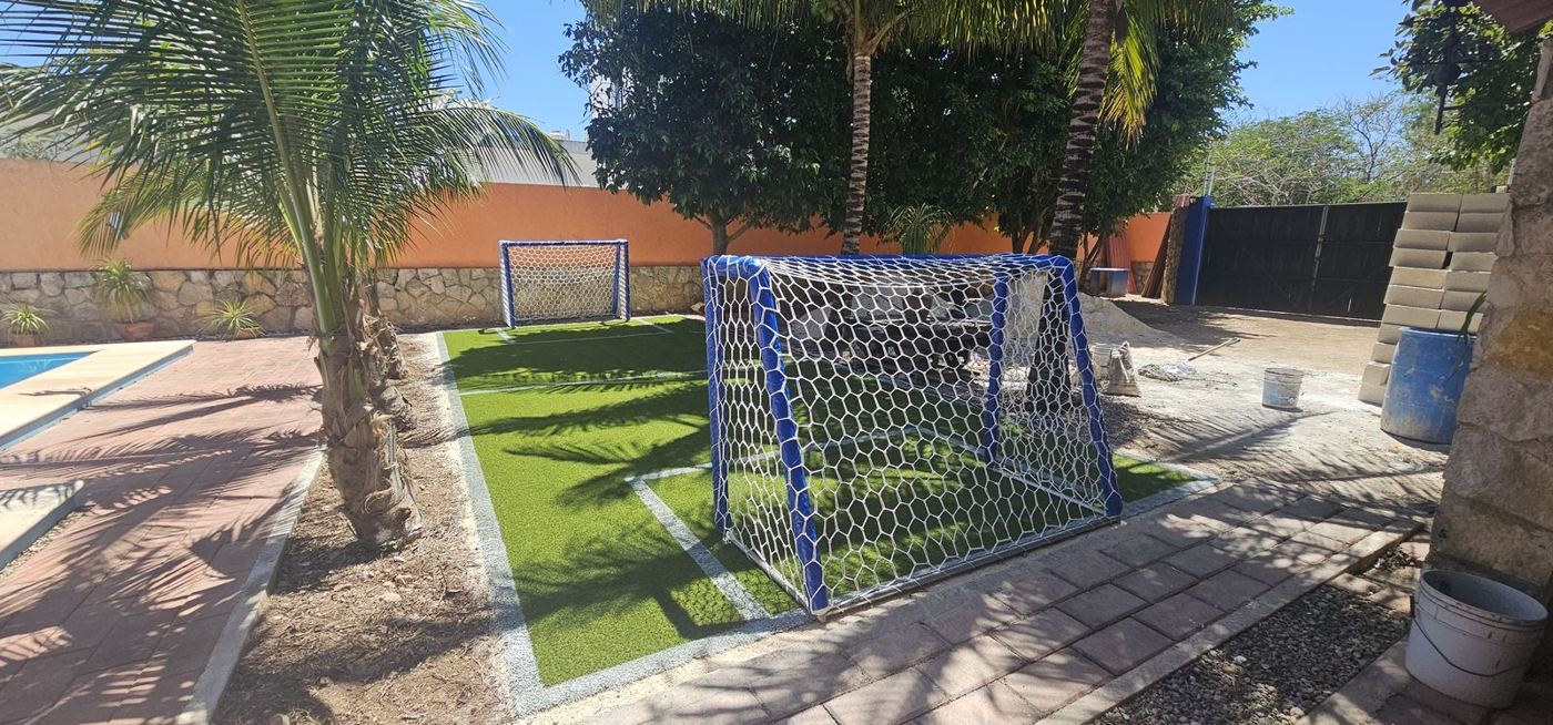 Portería de fútbol forrada en azul con red blanca en cancha de pasto sintético de jardín