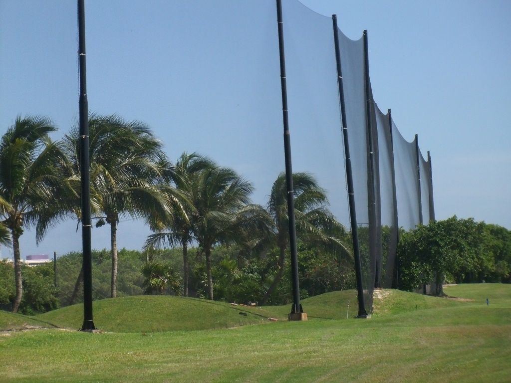 Red de contención para golf de gran altura con postes negros entre palmeras