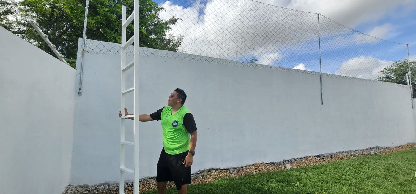 Red perimetral sobre barda blanca con postes metálicos tipo escalera