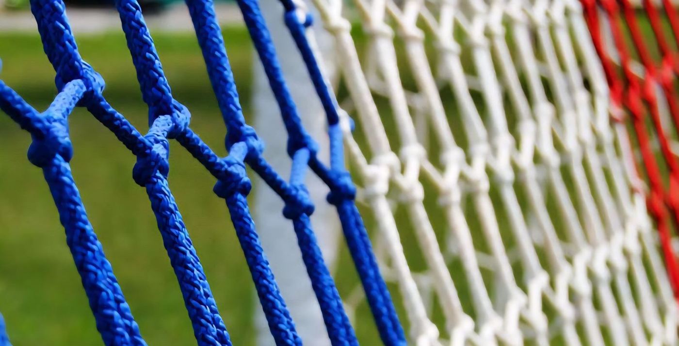Detalle de los nudos de una red para portería en azul, blanco y rojo