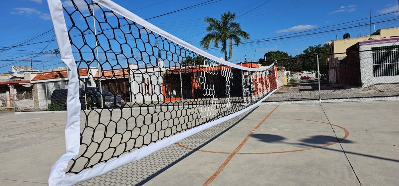 Red de voleibol negra con banda blanca en una cancha de concreto al aire libre