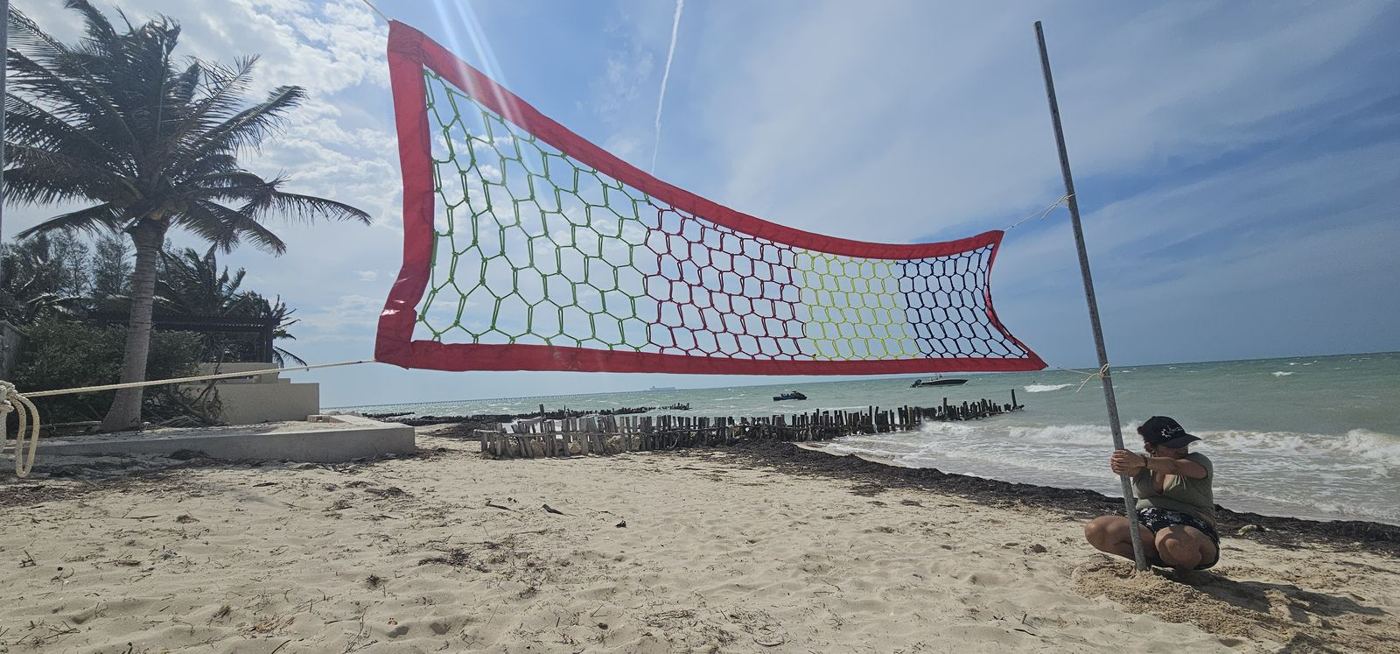 Instalación de una red de voleibol de playa con borde rojo frente al mar